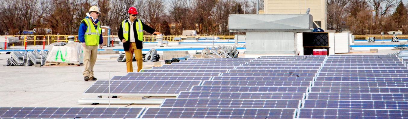 USPS workers on a roof with solar panels